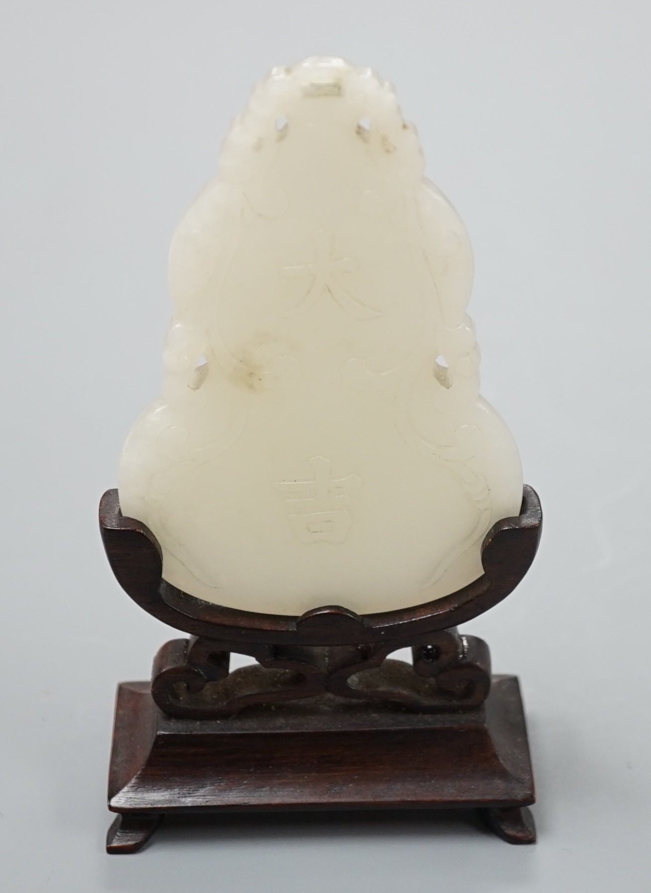 A Chinese inscribed white jade gourd shaped plaque on stand, with calligraphy, 12cms high.